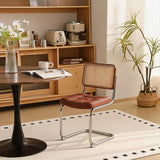 A modern dining chair with a brown tufted leather seat and a woven cane backrest, supported by a chrome cantilever frame, shown in a warm, styled dining room setting.