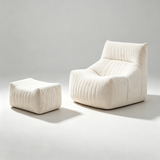 A cream-colored, ribbed fabric lounge chair with a matching ottoman, photographed in a minimalist studio setting with a light gray background.