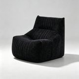 A modern low-profile armchair upholstered in a dark charcoal gray ribbed corduroy fabric, photographed on a light gray studio background with a soft shadow.