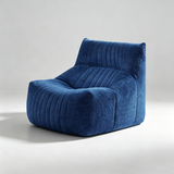 A modern low-profile lounge chair upholstered in textured blue fabric with vertical channel tufting, shown on a light gray studio background.