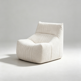 A modern low-profile armless lounge chair upholstered in textured off-white fabric with vertical channel tufting, shown on a light gray studio background.